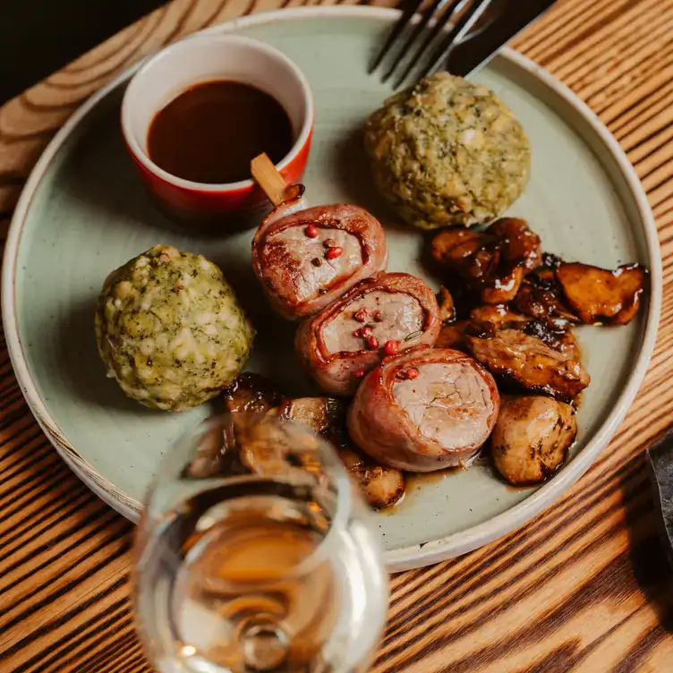 Teller mit Schweinemedaillons und Semmelknödeln zu Wein im Restaurant Jäger & Lustig, einem der besten Restaurants in Berlin.