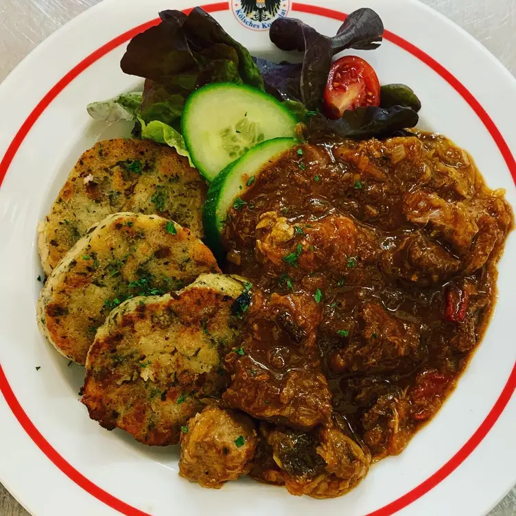 Herzhaftes Gulasch mit Knödeln auf einem Teller des „Kölschen Konsulats“ bzw. des Gaffel Haus Berlin an der Friedrichstraße, eines der besten deutschen Restaurants in Berlin