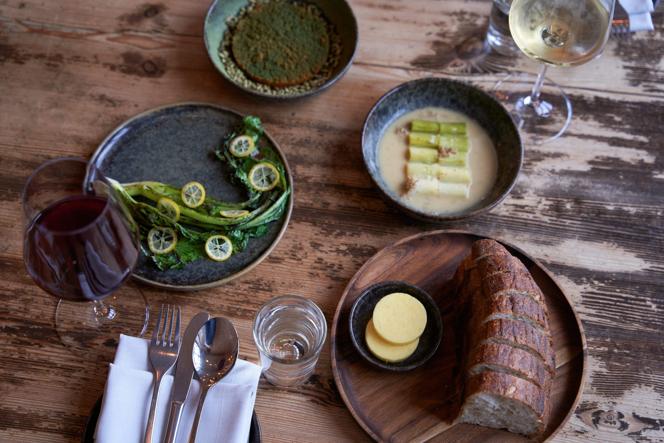 Ein gedeckter Tisch mit drei kleinen, Gemüse-basierten Speisen und Sauerteigbrot.