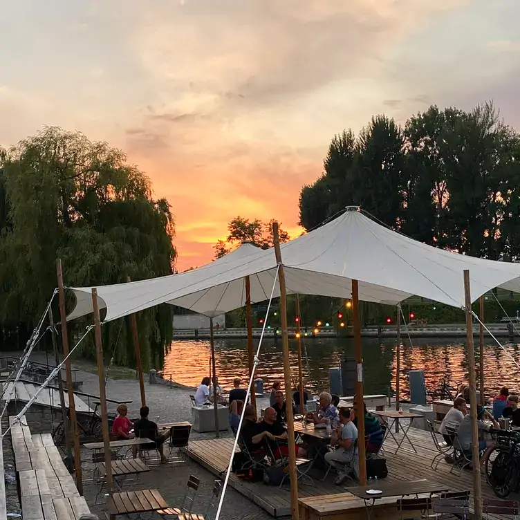 Lounge-Bereich mit Tischen, Bänken und Sonnensegeln direkt am Spreeufer in der Weltwirtschaft, einer der schönsten Dachterrassen in Berlin.