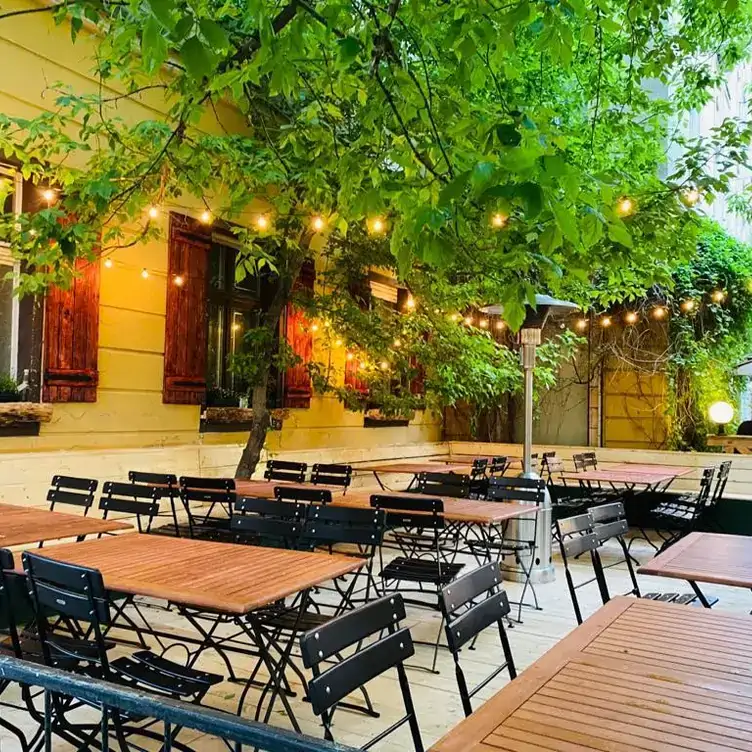 Terrasse mit Tischen und Stühlen vor der Fassade des Jäger & Lustig, einem der besten Restaurants mit Außenplätzen in Berlin.