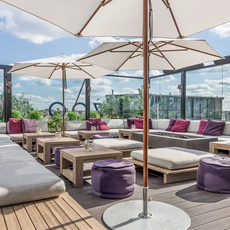 Blick über die Dachterrasse mit Sitzen, Tischen und Sonnenschirmen im GRACE Garden & Rooftop.