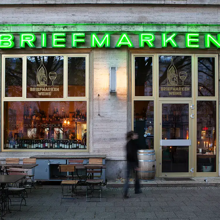 Eingang mit grüner Neonaufschrift und Plätzen im Außenbereich im Briefmarken Weine, einem der beliebtesten Restaurants mit Außenplätzen in Berlin.