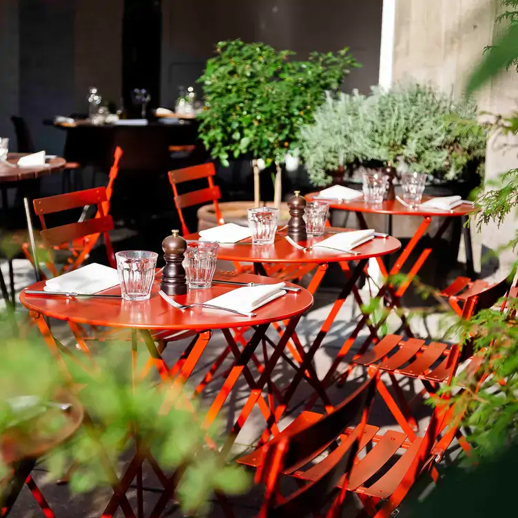 Rot lackierte Stühle im grünen Außenbereich des Restaurants Spindler in Berlin.