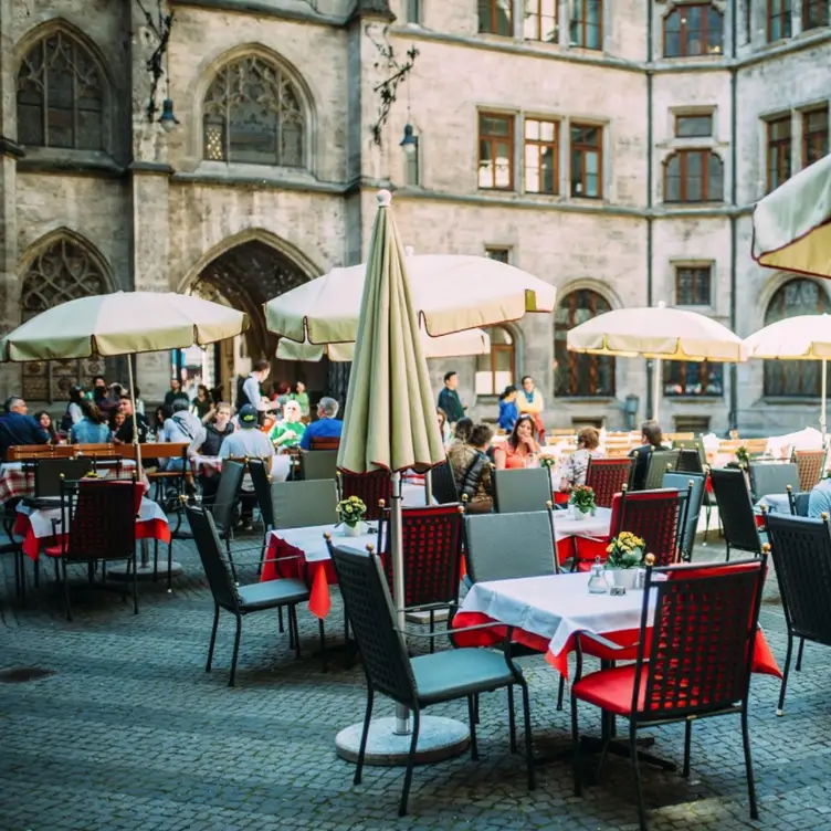 Außenbereich mit Tischen, Stühlen und Sonnenschirmen direkt auf dem Marienplatz im Ratskeller, einem der besten bayerischen Restaurants in München.