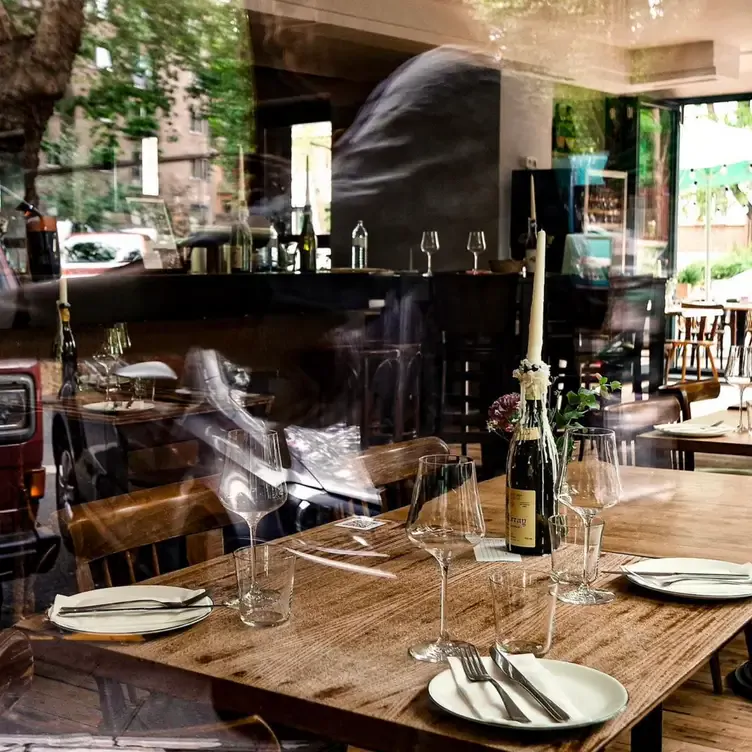 Das Interieur des Tanica, einem der romantischsten Restaurants in Köln, mit einem Holztisch, Weingläsern und Tellern.