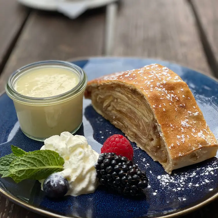 Österreichische Desserts wie Apfelstrudel mit Schlagsahne und Früchten werden im Garchinger Augustiner, einem der besten bayerischen Restaurants in München, serviert.