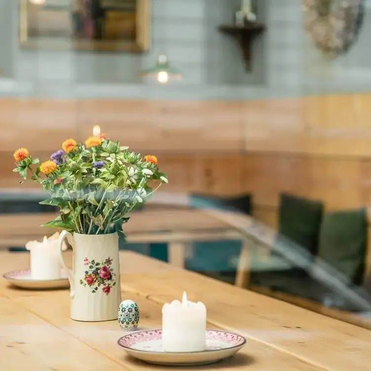 Holztisch mit Vase und Kerzen im Tiroler Design bei Marend Tiroler Küche Eimsbüttel, einem der besten romantischen Restaurants in Hamburg.