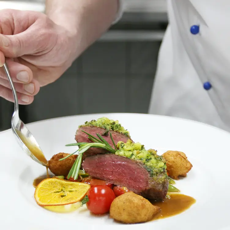 Elegant angerichtetes Bratenstück mit Sauce, Kartoffeln und Tomaten bei Pschorr, einem der besten bayerischen Restaurants in München.