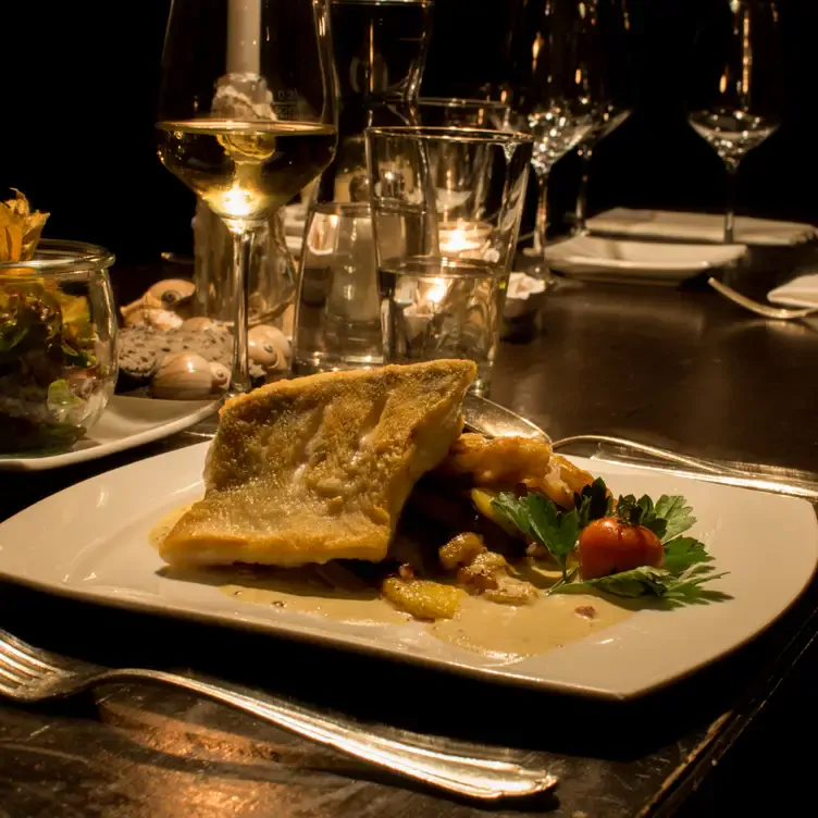 Paniertes Fischfilet auf Sauce, Pommes und Salat im Das Dorf, einem besonders romantischen Restaurant in Hamburg.