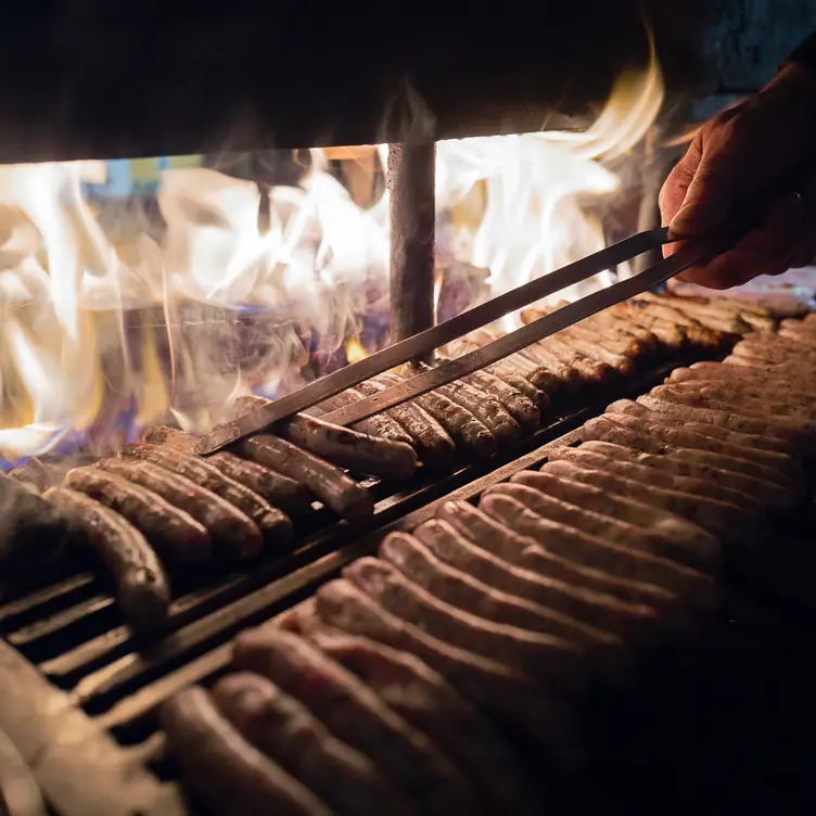 Die kleinen Rostbratwürstchen garen auf dem offenen Buchenfeuergrill im Nürnberger Bratwurst Glöckl am Dom, einem der besten bayerischen Restaurants in München.