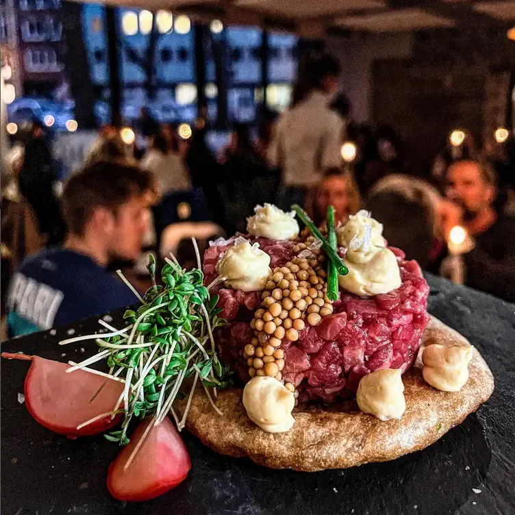 Ein frisches Tatar mit Spargel vor dem Hintergrund des Restaurants Tanica, einem durch und durch romantischen Restaurant in Köln.