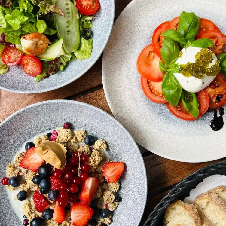 Drei Teller mit Salaten und Müsli sowie Brotkorb im Mélange, einem Insidertipp für den besten Brunch in Hamburg.