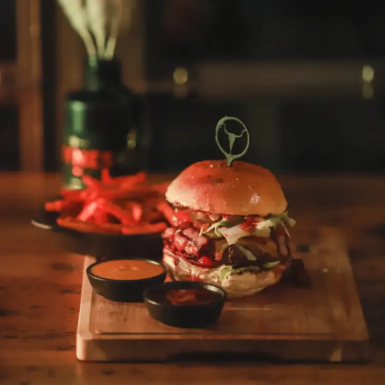 Saftiger Burger mit Dips und Pommes auf Holzbrett serviert im Upper Grill.