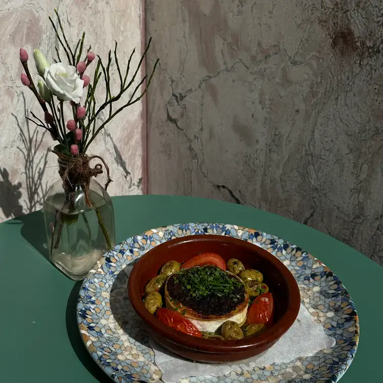 Überbackener Ziegenkäse mit Tomaten und Oliven im Tongefäß im Café Karin, einem Lokal mit einem der besten Brunchs in Frankfurt.