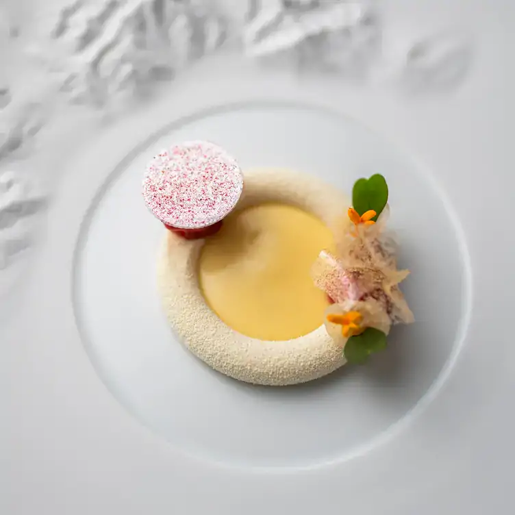 47739143 Ein rundes weißes Dessert mit Dekorationen bei ES:SENZ, einem der MICHELIN-Sterne-Gewinner von 2024.