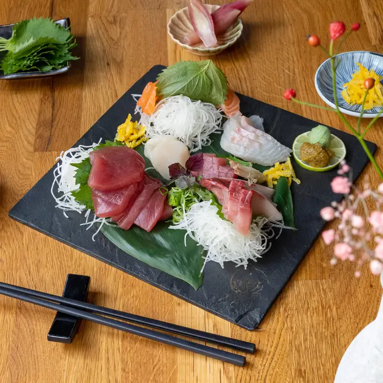 Sashimi auf einer schwarzen Steinplatte mit verschiedenen Beilagen in einem der besten Kölner Restaurants für besondere Anlässe.