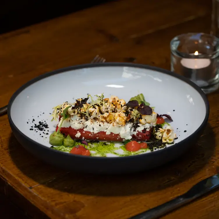 Schön angerichtetes Gericht auf einem weißen Teller und einem braunen Holztisch im Amabile, einem der besten Restaurants in Köln für besondere Anlässe.