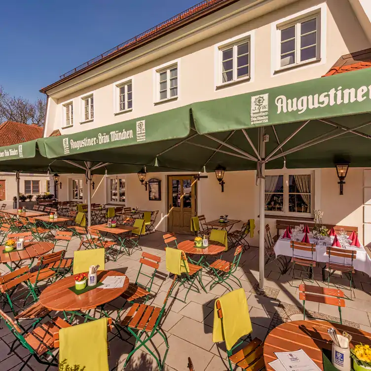 Außenbereich mit Sonnenschirmen und Tischen im Garchinger Augustiner, einem der besten Biergärten in München.