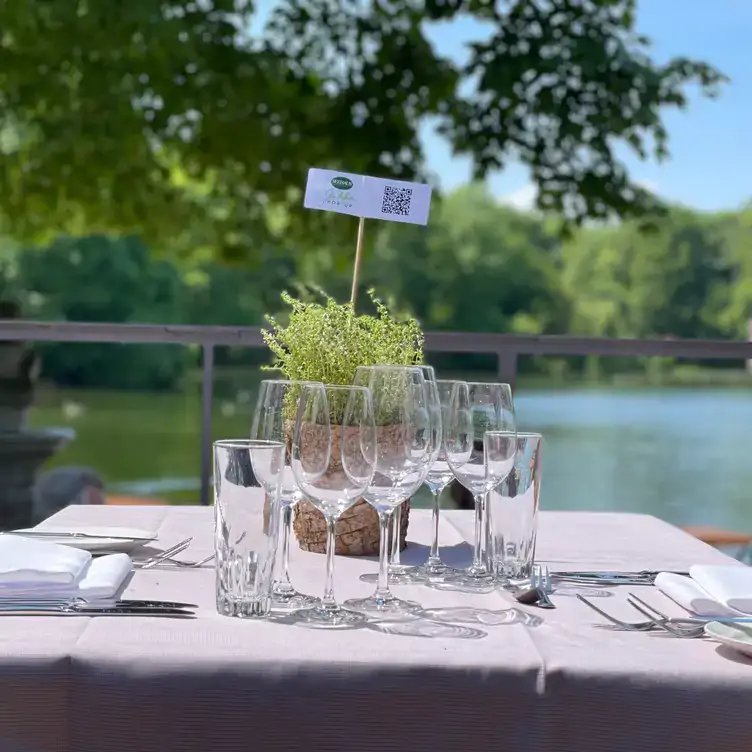 Gedeckter Tisch mit Gläsern und Besteck im Seehaus im Englischen Garten, einem der besten Biergärten in München.