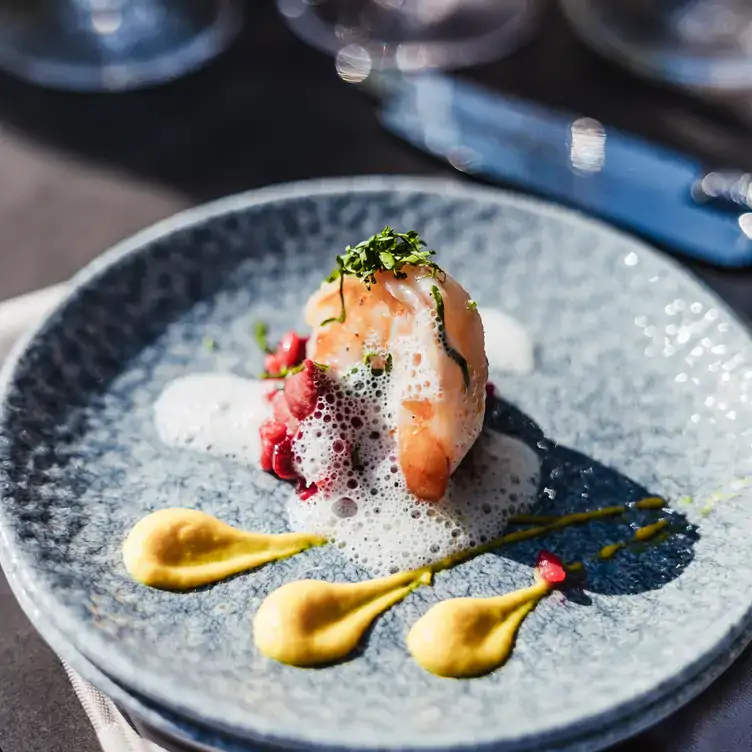 Teller mit kreativ angerichtetem Fischgericht und Schaumhaube im Blue Mare, einem der besten Fischrestaurants in Hamburg.