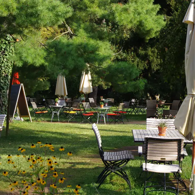 A garden with tables and white umbrellas at Café in der Gartenakademie, one of the best cafés in Berlin.