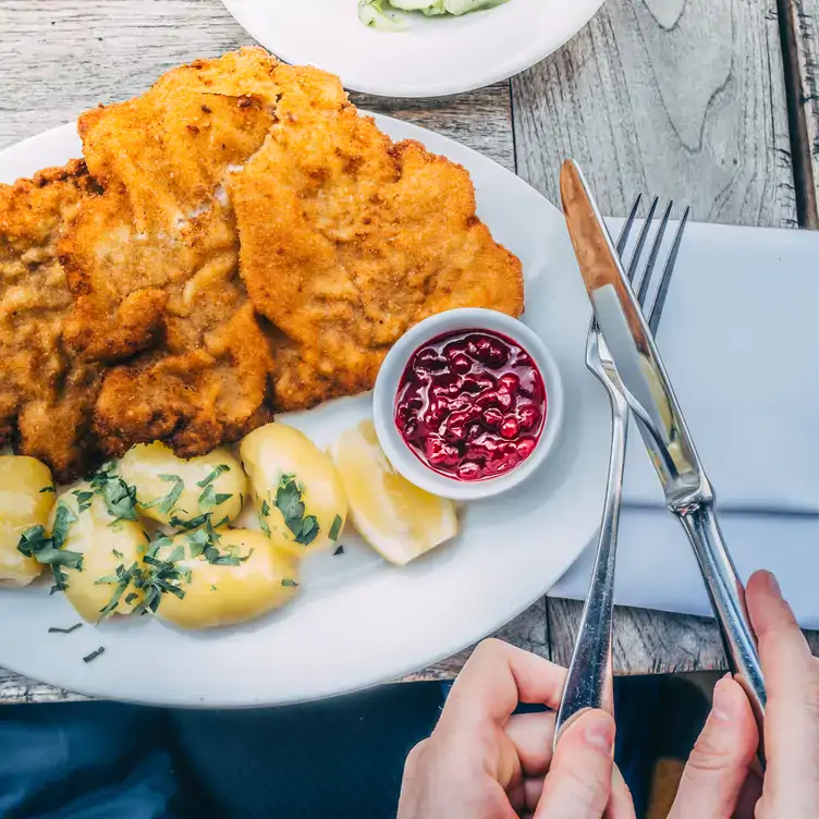 A traditional schnitzel with red sauce and potatoes at Einstein Unter den Linden, one of the best traditional restaurants in Berlin.