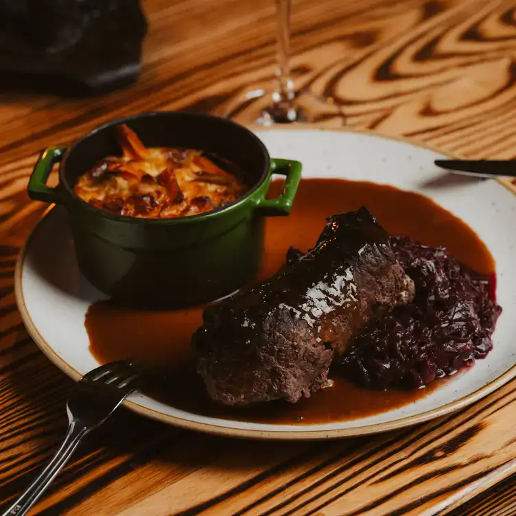 A meat dish with red jus and a casserole of potatoes at Restaurant Jäger & Lustig, one of the best German Restaurants in Berlin.