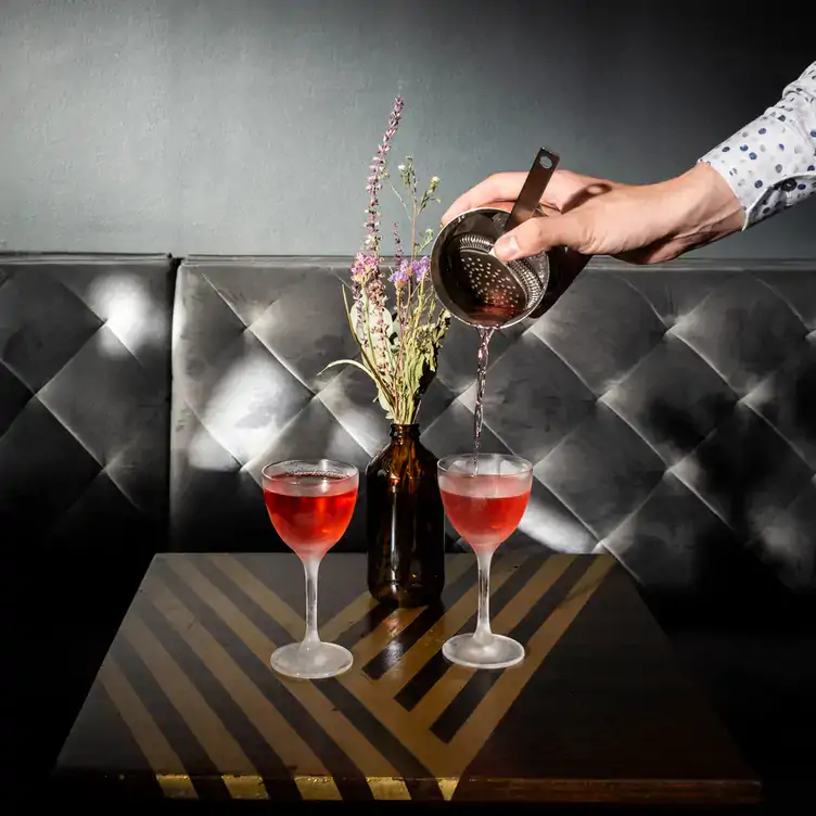 Two cocktails being poured at a table at Velvet, one of the best cocktail bars in Berlin.