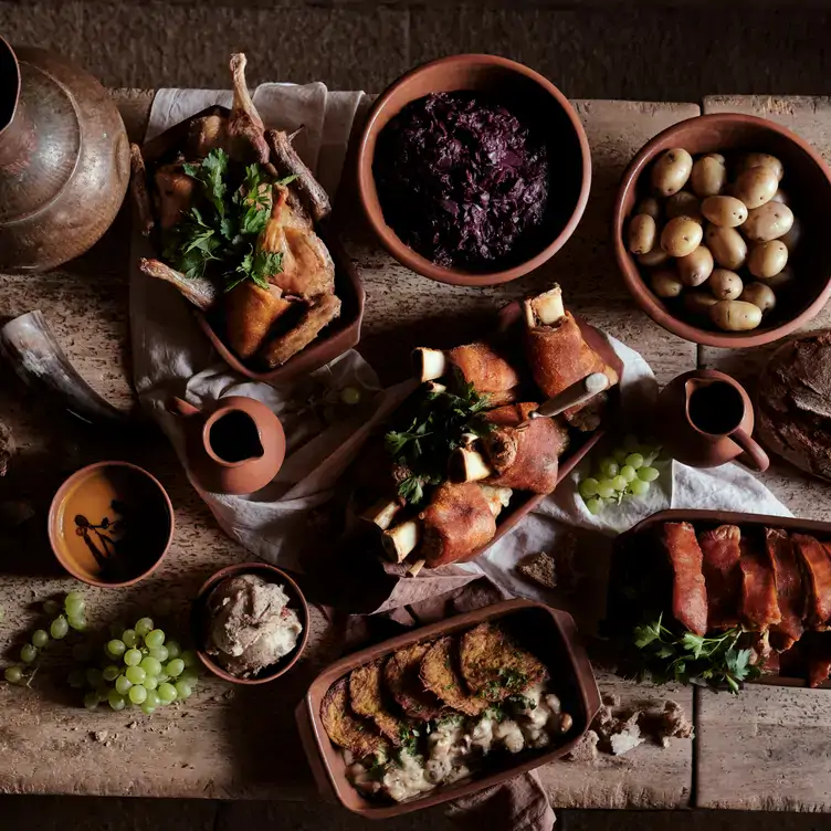 Wuchtiger Holztisch mit rustikalen Gerichten mit Mittelalterthema in der Tafelrunde, einem der besten Restaurants für Gruppen in Berlin.