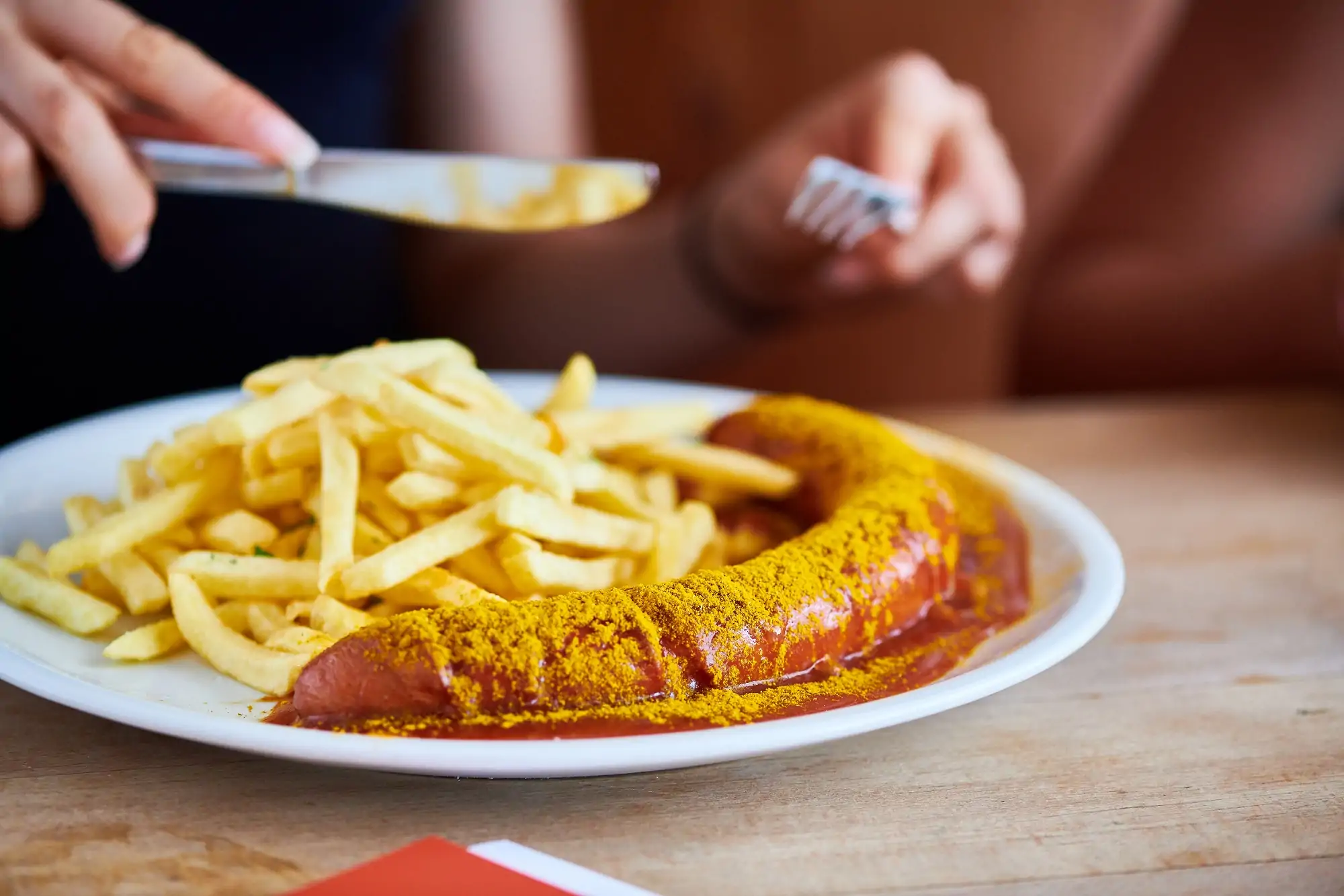 Teller mit Currywurst und Pommes.