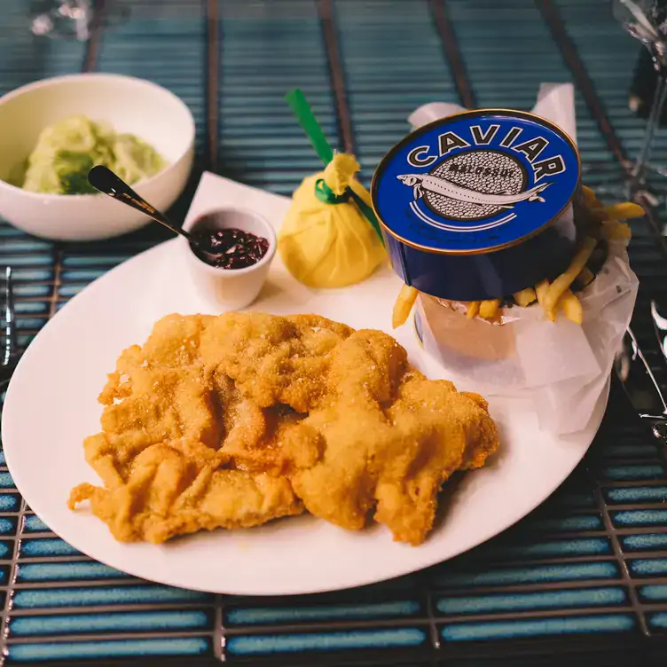 Schnitzel mit Preiselbeeren, Gurkensalat, Pommes Frites und einer Dose Kaviar im Restaurant Claas.