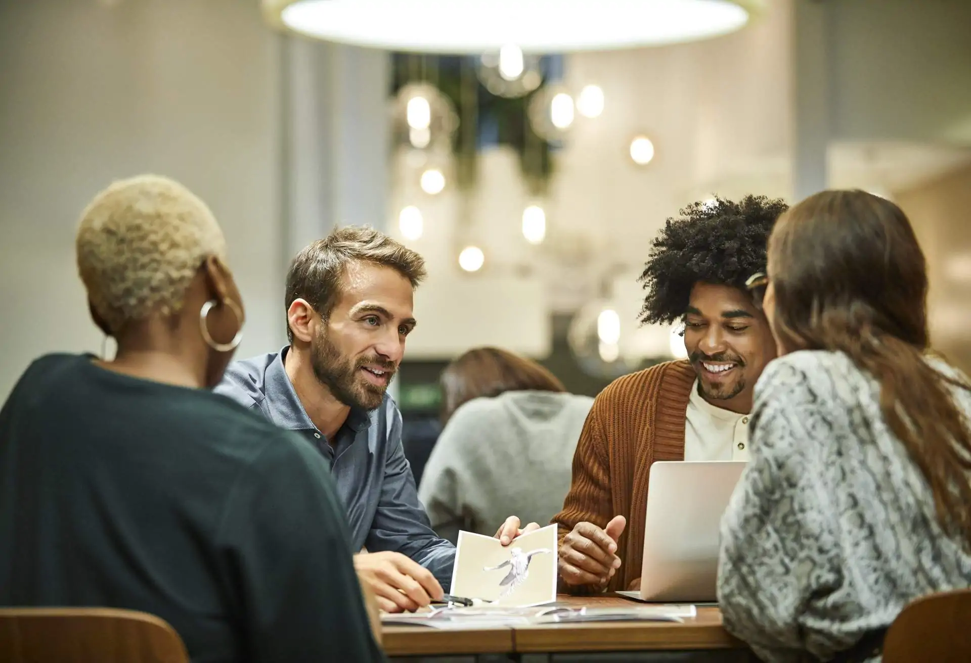 Multi-ethnic business professionals discussing at desk. Male and female coworkers are working in office. They are in meeting.